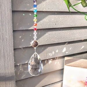 May include: A crystal suncatcher with a clear teardrop-shaped crystal, a silver lotus charm, and a rainbow of beads.