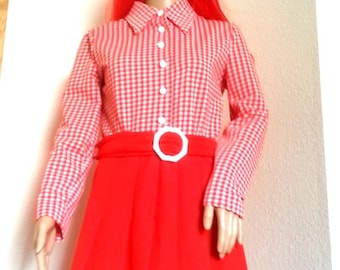 May include: A red and white gingham print shirt dress with a pleated skirt. The dress features a white belt with a geometric buckle. The dress is displayed on a mannequin with a red wig.