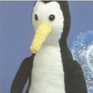 Può includere: Un peluche a forma di pinguino con corpo bianco e nero, becco giallo e due occhi neri. Il pinguino presenta un petto e un'area del viso bianchi, con una colorazione nera sui lati e sul retro della testa e del corpo, su uno sfondo blu.