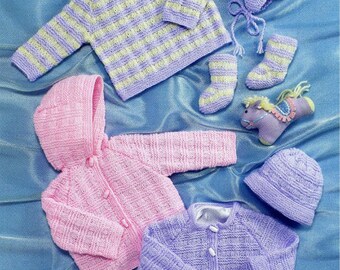 May include: A collection of knitted items including a lavender and yellow striped sweater, a matching hat with earflaps, and socks. Also included are a pink hooded cardigan, a solid lavender cardigan with buttons, a plain hat, and two small toy horses.