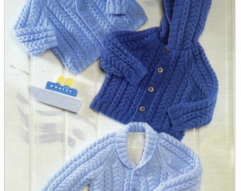 May include: Three knitted cardigans in shades of blue featuring intricate cable knit patterns. One cardigan is a deep blue with a hood and buttons, while the other two are lighter blue with V-neck and shawl collar designs, accompanied by a toy boat.