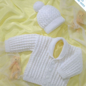 May include: A white knitted baby cardigan with a shawl collar and four buttons, paired with a matching white knitted hat featuring a pom-pom. The set includes text that reads INCLUDES PREMATURE SIZES, indicating availability for smaller infants.