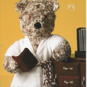 May include: A plush teddy bear with shaggy brown fur wearing wire-rimmed glasses and a white knitted bathrobe with a braided belt. The bear holds a small dark red book. Text on the pattern cover reads Wendy, Shimmer, 5068, and Height 46cms (18ins).