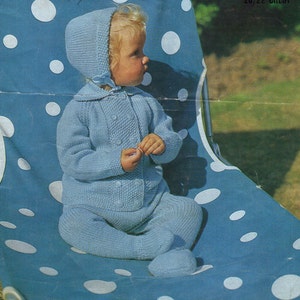 May include: A light blue knitted baby outfit consisting of a long-sleeved jacket with a collar and double-breasted button closure, matching footed leggings, and a matching bonnet with a tie under the chin. The set features a textured knit pattern.