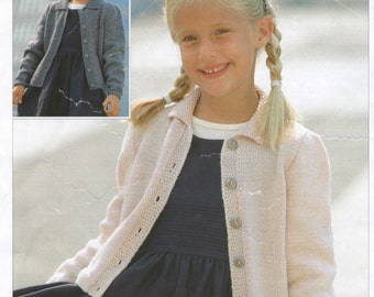 May include: A pale pink long-sleeved knit cardigan featuring a collared neckline and a front button closure, worn over a dark navy blue dress with a pleated bodice. The cardigan has a textured knit pattern and is shown in two different views.