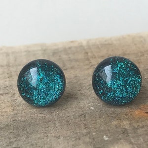 May include: A pair of teal blue glass earrings with a sparkly finish.