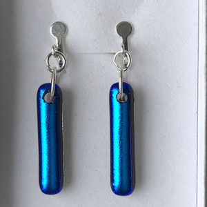 May include: A pair of blue glass dangle earrings with silver clip-on backs.