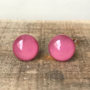 May include: A pair of pink glass earrings. The earrings are round and have a shiny finish.