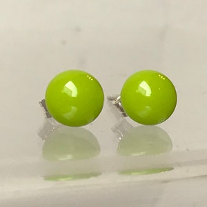 May include: A pair of lime green glass stud earrings with silver posts.