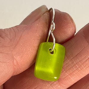 Op de afbeelding: Een rechthoekige oorknop van limoengroen glas met een zilveren haak.