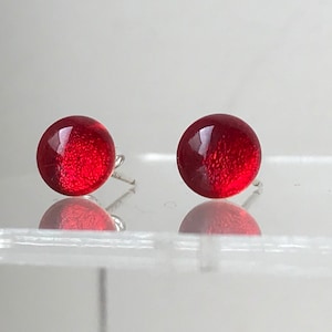 Könnte beinhalten: Ein Paar rote Glas-Ohrstecker mit silbernen Stiften.