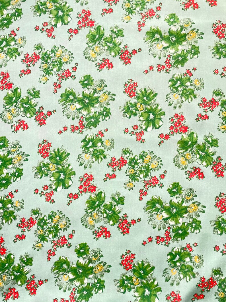 May include: A light green fabric with a repeating pattern of green, red, and yellow floral bouquets.