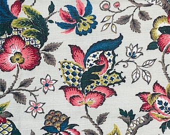 May include: Close-up of a floral fabric with a cream background. The design features large, stylized flowers in shades of pink, teal, green, and yellow, with brown stems and leaves. The pattern is detailed and intricate, creating a vintage aesthetic.
