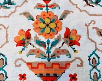 May include: A white fabric with a repeating pattern of stylized flowers in shades of orange, red, yellow, brown, and teal. The flowers are arranged in a vase with a geometric pattern.