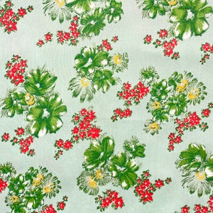 May include: A light blue fabric with a repeating pattern of green and white flowers with red accents.