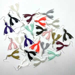 May include: A collection of 18 pairs of earrings, each featuring a unique anatomical design. The earrings are made of a variety of colors, including pink, orange, purple, green, gold, and gray. The earrings are all made of a smooth, shiny material.