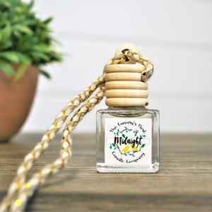 May include: A clear glass bottle with a wooden cap and a gold and white braided cord. The bottle has a label that says "The Canary's Nest Midnight Candle Company".
