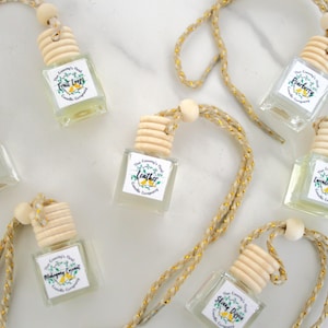 May include: Eight small glass bottles with wooden tops and string hangers. Each bottle contains a clear liquid and has a label with a different scent name, including "Fruit Loops", "Leather", "Midnight", "Sleepy Citrus", "Lavender Vanilla", "Raspberry", and "Mango Coconut".