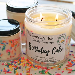 Clear, sleek jar candle with black lid. The candle scent is Birthday Cake and the wax is white with rainbow sprinkles around the edges of the jar.