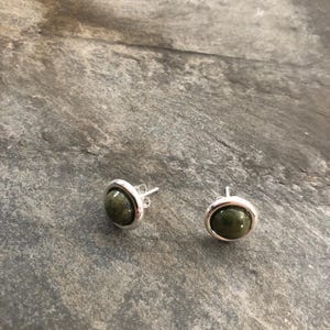 Könnte beinhalten: Ein Paar silberne Ohrstecker mit grünen Edelstein-Akzenten.