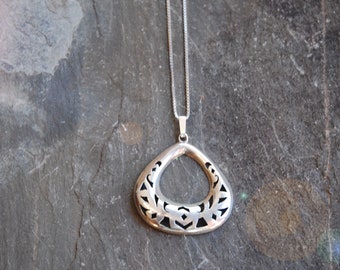 Può includere: Una collana con ciondolo in argento, con un delicato design traforato. Il ciondolo ha la forma di una lacrima con intricati tagli.