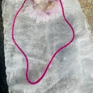 Może przedstawiać: Naszyjnik z różowych kamieni szlachetnych ze srebrnym zapięciem. Naszyjnik wykonany jest z małych, okrągłych koralików i jest prezentowany na białym tle.