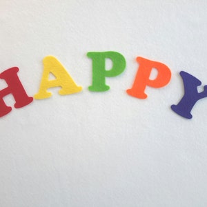 May include: The word "HAPPY" spelled out in colourful felt letters. The letters are red, yellow, green, orange, and purple.