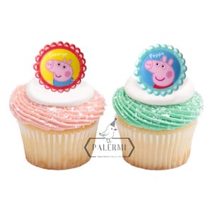 May include: Two pink and green cupcakes with white frosting and edible Peppa Pig character toppers. The toppers are red and blue with white scalloped edges. The pink cupcake has a topper that says "George" and the green cupcake has a topper that says "Peppa".