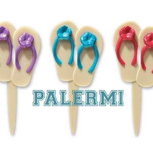 May include: Set of six cupcake toppers featuring flip-flop sandals with flower embellishments in purple, blue, and red.