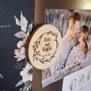 May include: A wooden round slice with a decorative wreath design and the text "Eric and Kayla June 6, 2022".