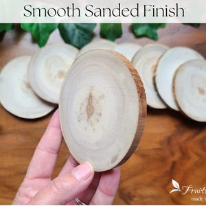 May include: Close-up of a smooth sanded wood slice, showing the natural grain of the wood. The wood slice is light brown in colour and has a slightly rounded edge. The wood slice is part of a set of wood slices, all of which are arranged in a circle on a wooden surface. The text "Smooth Sanded Finish" is visible at the top of the image.