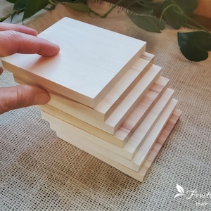 May include: A stack of six unfinished wooden squares, each with a smooth, light wood grain. The squares are stacked in a staggered pattern, creating a visually appealing display.