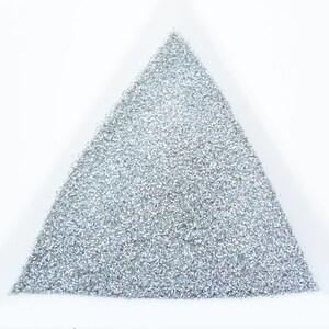 May include: A triangular container filled with silver glitter.