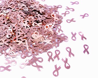 May include: A large pile of rose gold glitter confetti shaped like ribbons. The confetti is scattered on a white background.