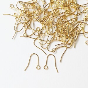 May include: A pile of gold-coloured earring hooks, a type of jewellery finding.