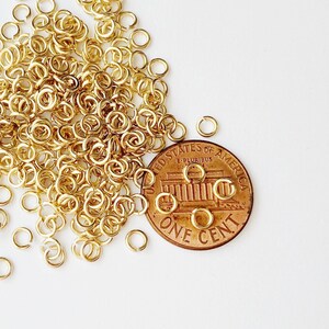 May include: A pile of gold jump rings, approximately the size of a UK penny.