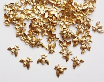 May include: A large pile of gold-colored metal bee charms. The bees are detailed and have a textured surface.