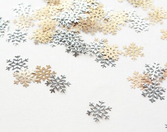 May include: A white background with a scattering of silver and gold snowflake confetti.