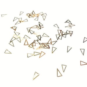 May include: A scattering of gold-coloured metal triangle confetti on a white background.