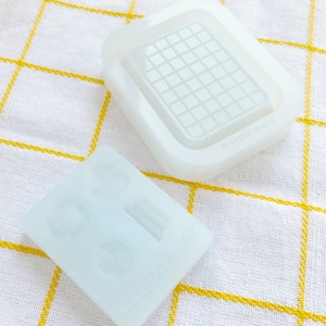 May include: Two clear silicone molds for making resin crafts. One mold has a grid pattern and the other has three round shapes.