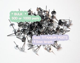 May include: A pile of silver-colored titanium earring posts. The posts have a flat, round disc and a 9.5mm length. Text on the image reads "BULK 500 or 1000 posts" and "6mm TITANIUM POSTS".