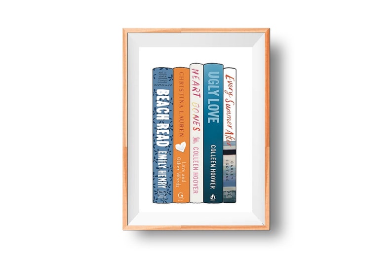 May include: A framed print featuring a stack of five books with colorful spines. The titles include "Beach Read," "Heart Bones," and "Ugly Love." The books are arranged vertically, with the titles and authors clearly visible.