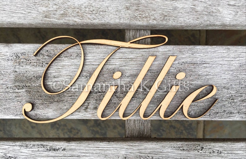 May include: A wooden sign with the name "Tillie" written in a cursive font.