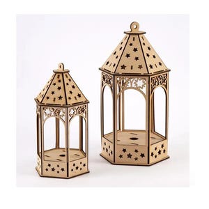 May include: Two wooden lanterns with star cutouts and decorative arch designs. The lanterns have a hexagonal base and a peaked roof. The wood has a natural, light brown colour. The lanterns are of different sizes.