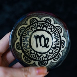 May include: A small ceramic dish with a black and white mandala design. The center of the dish features the astrological symbol for Virgo.