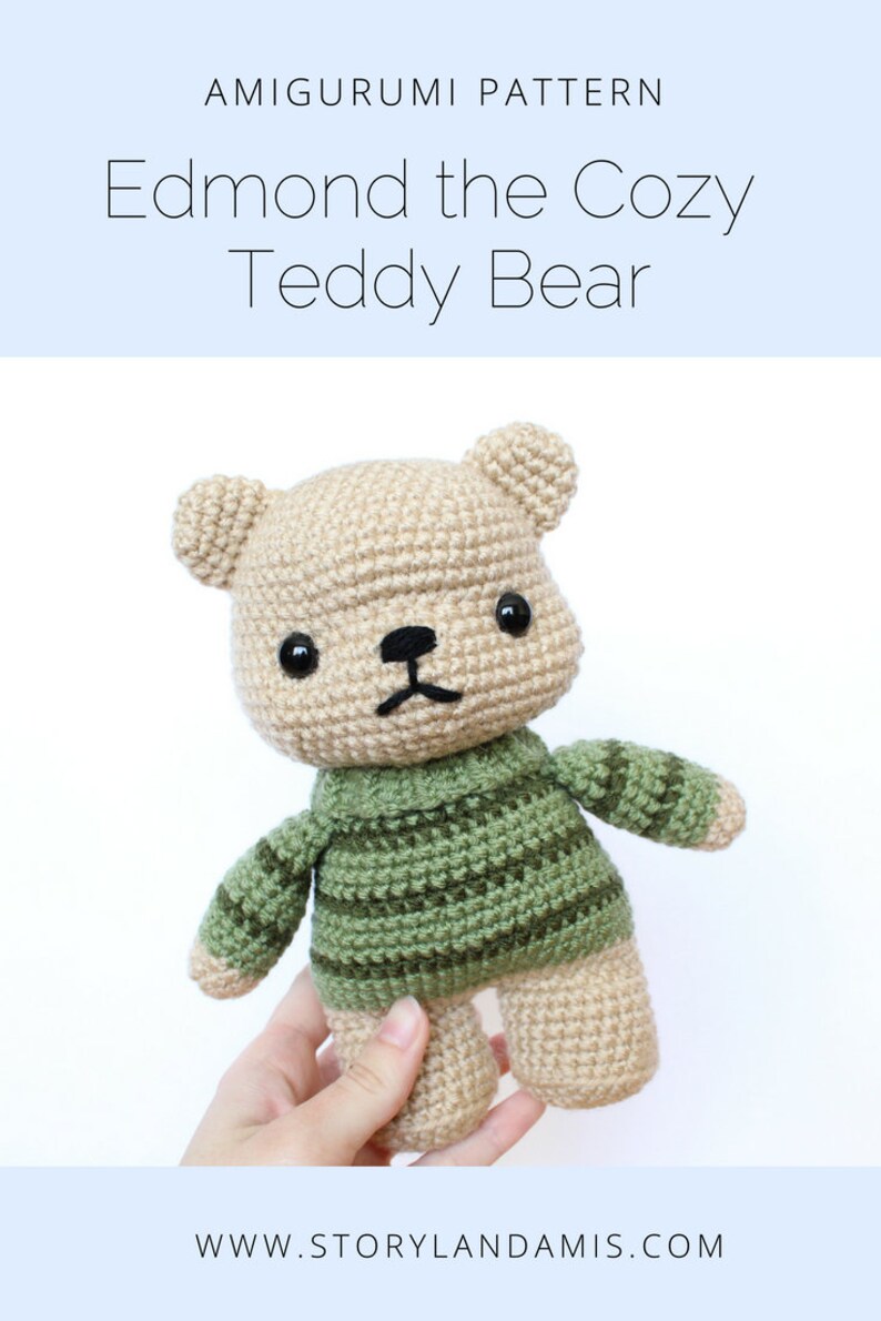 May include: A crocheted teddy bear wearing a green and brown striped sweater. The bear has black eyes and a black nose. The bear is being held by a hand. The text "Edmond the Cozy Teddy Bear" is at the top of the image. The text "www.storylandamis.com" is at the bottom of the image.