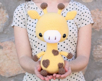 May include: A crocheted giraffe stuffed animal with brown spots and a yellow body. The giraffe has large black eyes and a white nose.