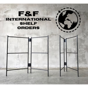 May include: Two black metal folding shelves with three shelves each. The shelves are standing on a concrete floor in front of a concrete wall. The text "F&F INTERNATIONAL SHELF ORDERS" is on the wall above the shelves. A black and white globe with a dashed circle around it is on the wall to the right of the shelves.