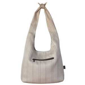 Könnte beinhalten: Eine beige und braune gestreifte Tragetasche mit einem geknoteten Griff und einer Reißverschlusstasche.