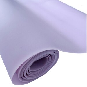 May include: A rolled-up sheet of lavender-colored material. The material appears to be smooth and flexible, with visible layers from the rolled form. The color is a soft, muted purple.